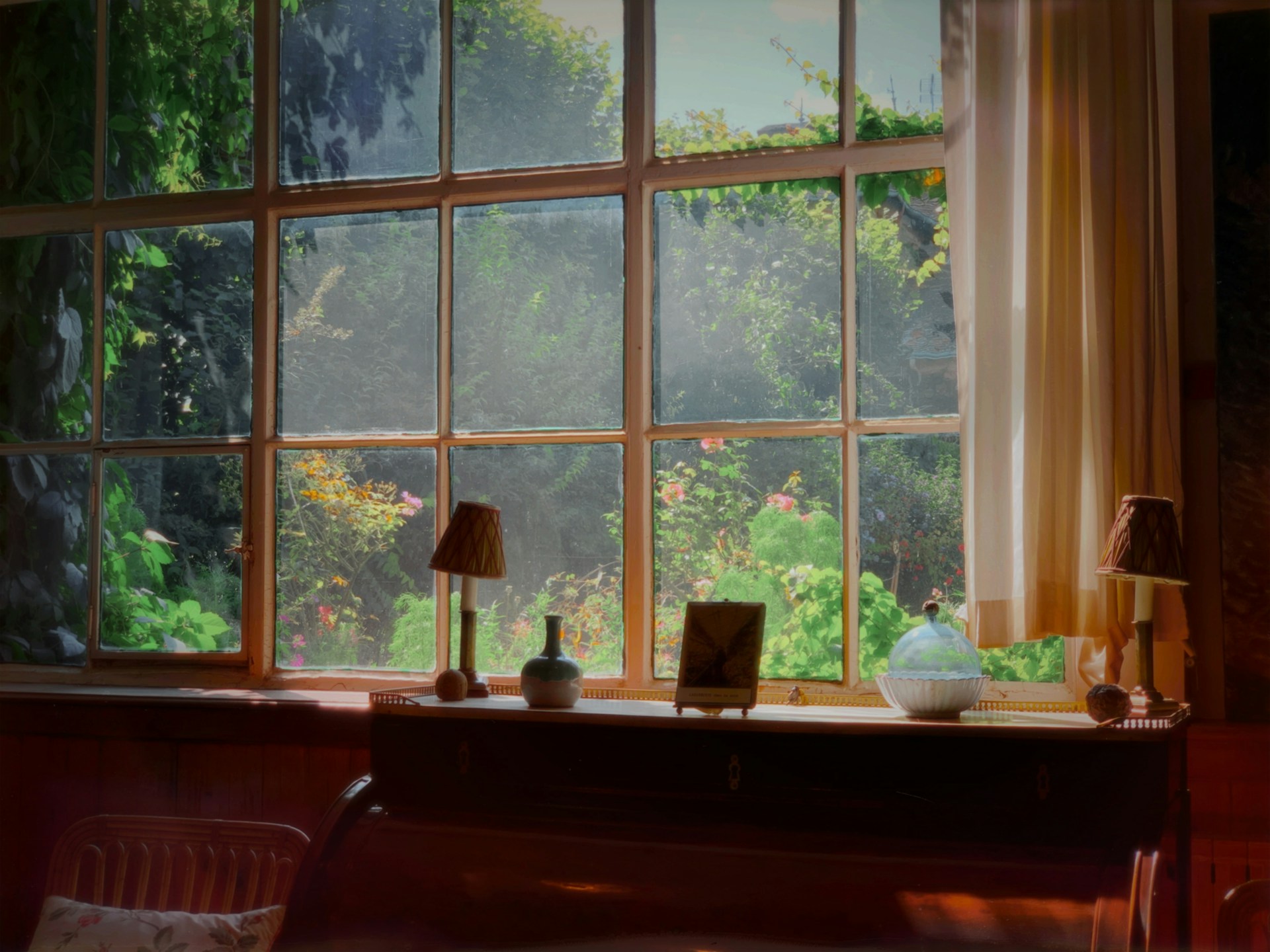 A large window in a home, overlooking a lively green garden.
